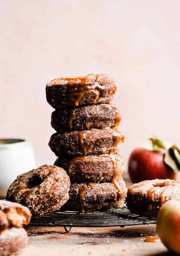 A stack of baked apple cider donuts drizzled with salted caramel sauce.