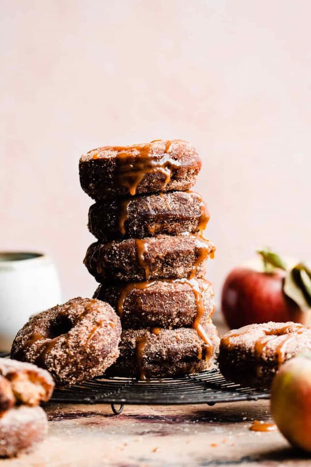 A stack of baked apple cider donuts drizzled with salted caramel sauce.