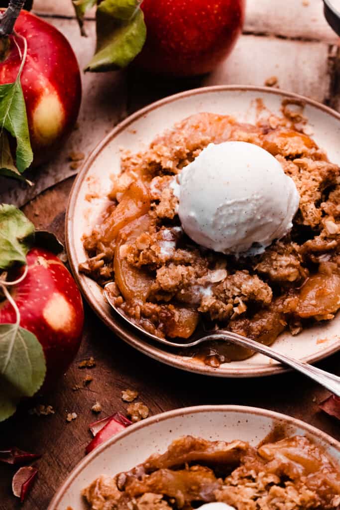 Plates of apple crisp topped with scoops of ice cream.