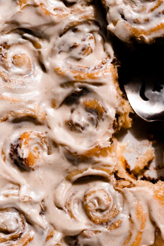 A top-down view of frosted cinnamon rolls in a pan.