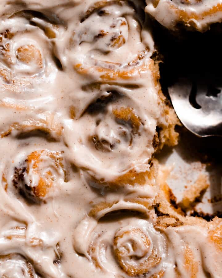 Cinnamon rolls in a pan frosted with cream cheese icing.