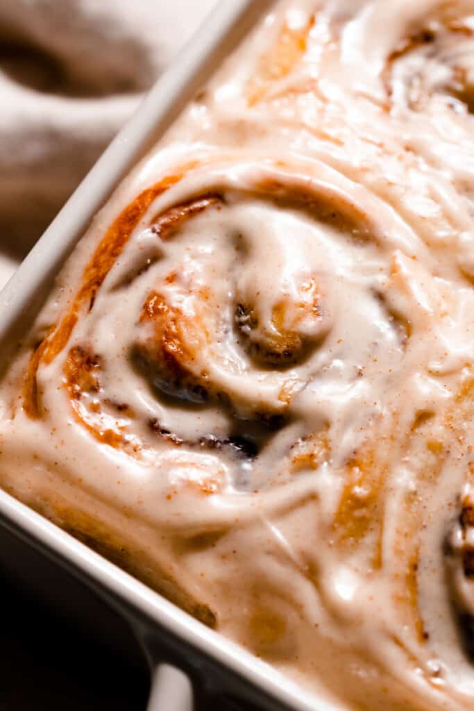 A close-up of a frosted brioche cinnamon roll.