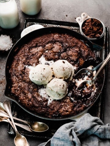 A pan of the chocolate pudding cake with spoons digging in, and scoops of ice cream on top.