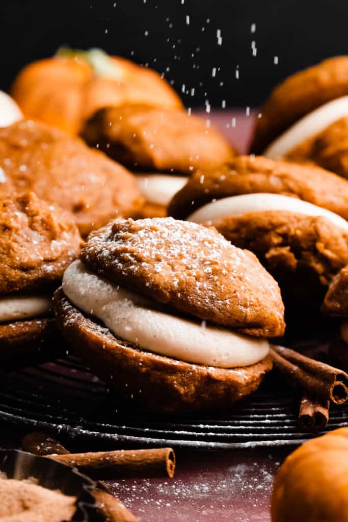 A close-up of a whoopie pie being dusted with powdered sugar. 