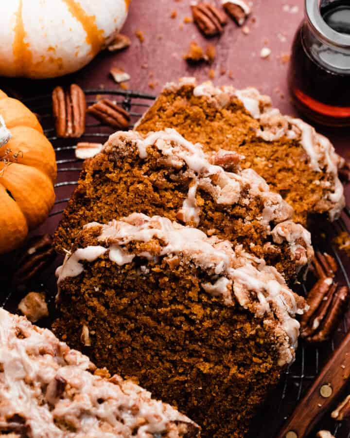 Slices of the pumpkin bread on a vintage cooling rack topped with pecan streusel and maple glaze.