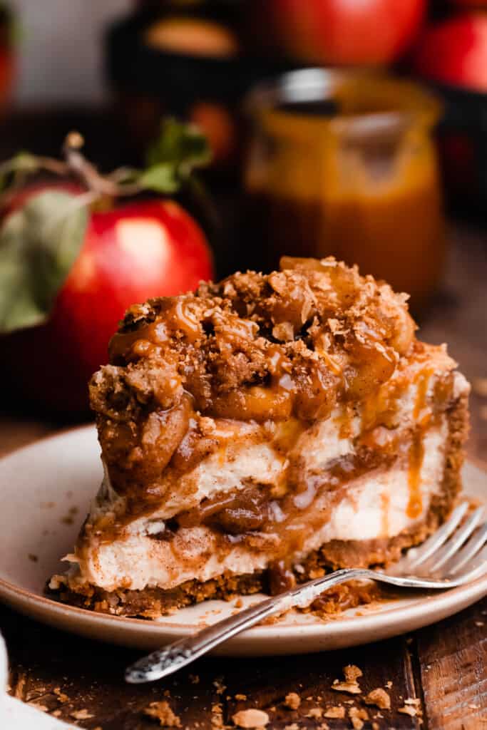A close-up on a slice of the caramel apple pie cheesecake on a plate.