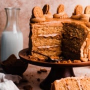 The sliced open biscoff cake on a cake stand, with swirls of frosting and biscoff cookies on top of the cake.