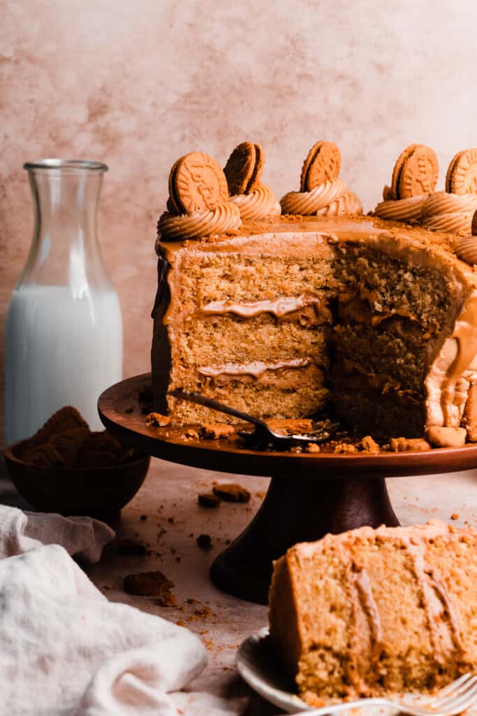 The sliced open three-layer Biscoff Cake on a cake stand, topped with swirls of frosting.  