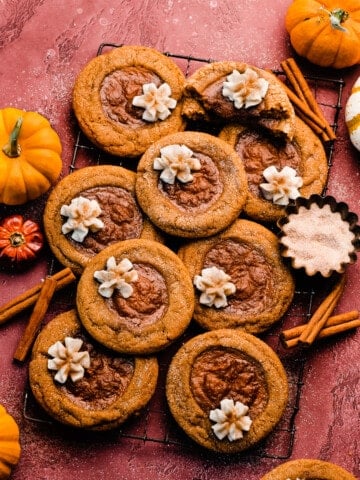 A wide angle photo of the pumpkin pie cookies on a vintage wire rack on a burgundy background.