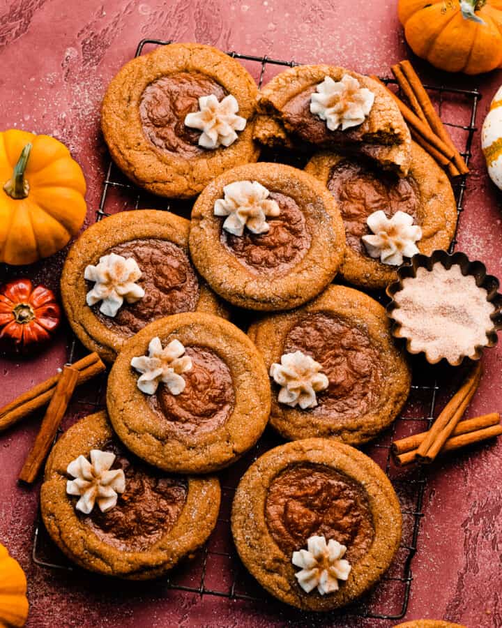 A wide angle photo of the pumpkin pie cookies on a vintage wire rack on a burgundy background.