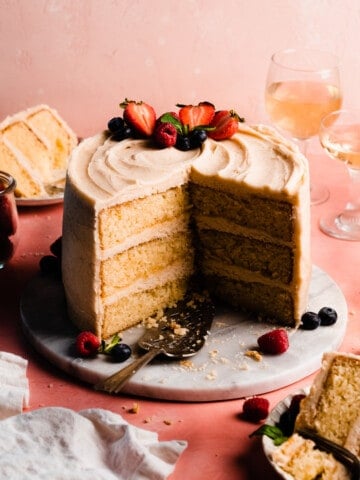 The sliced open 8-inch cake frosted in brown butter frosting and topped with fresh berries.