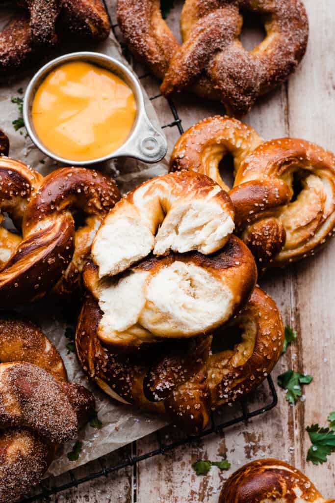 Soft pretzels on a vintage wire rack, with one broken open to show the fluffy insides. 