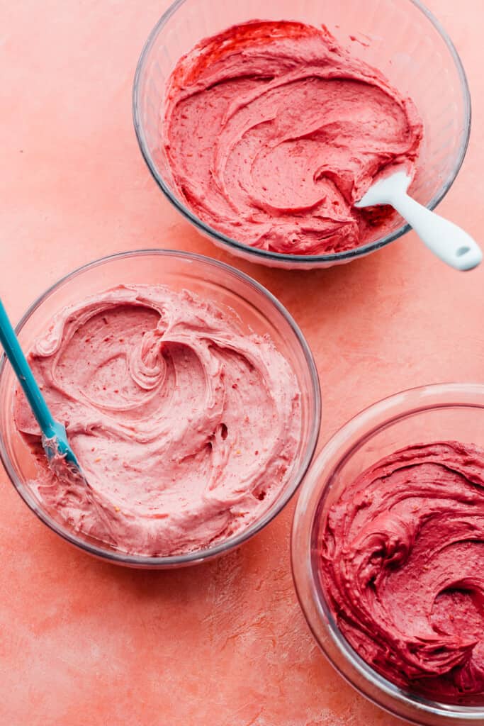 Bowls of raspberry frosting in various shades of pink. 