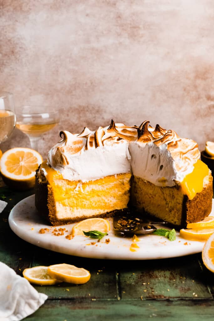 The sliced lemon meringue cheesecake on a marble plate.