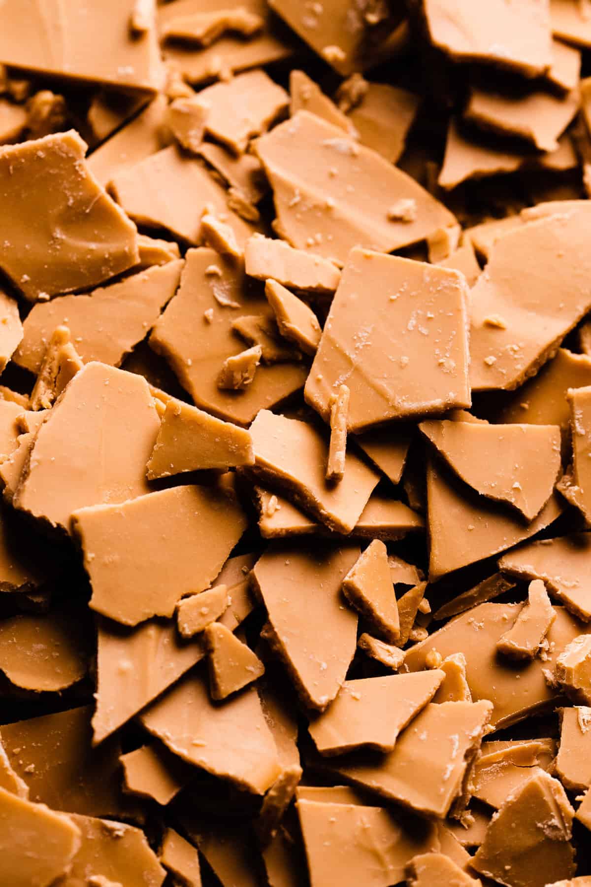 A close-up of chunks of caramelized white chocolate. The pieces are a deep caramely color.