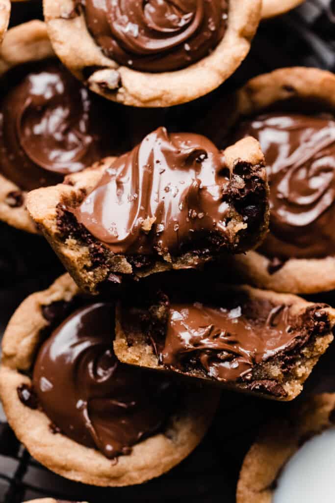A close-up on two halves of a chocolate chip cookie cup filled with nutella.