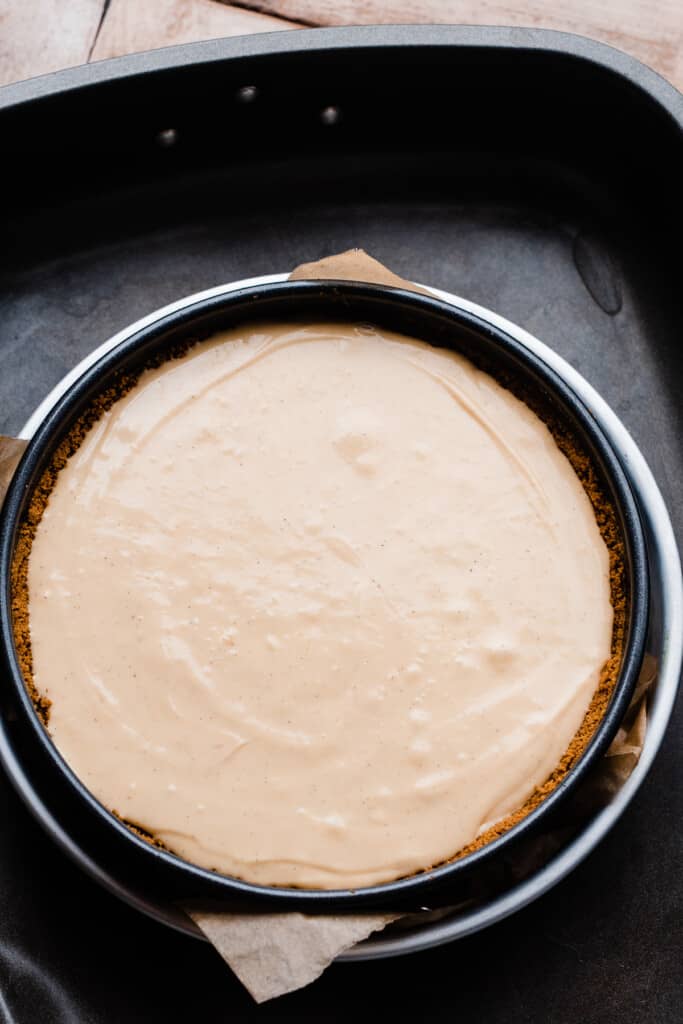 The unbaked cheesecake in the 10-inch pan, inside the roasting pan.
