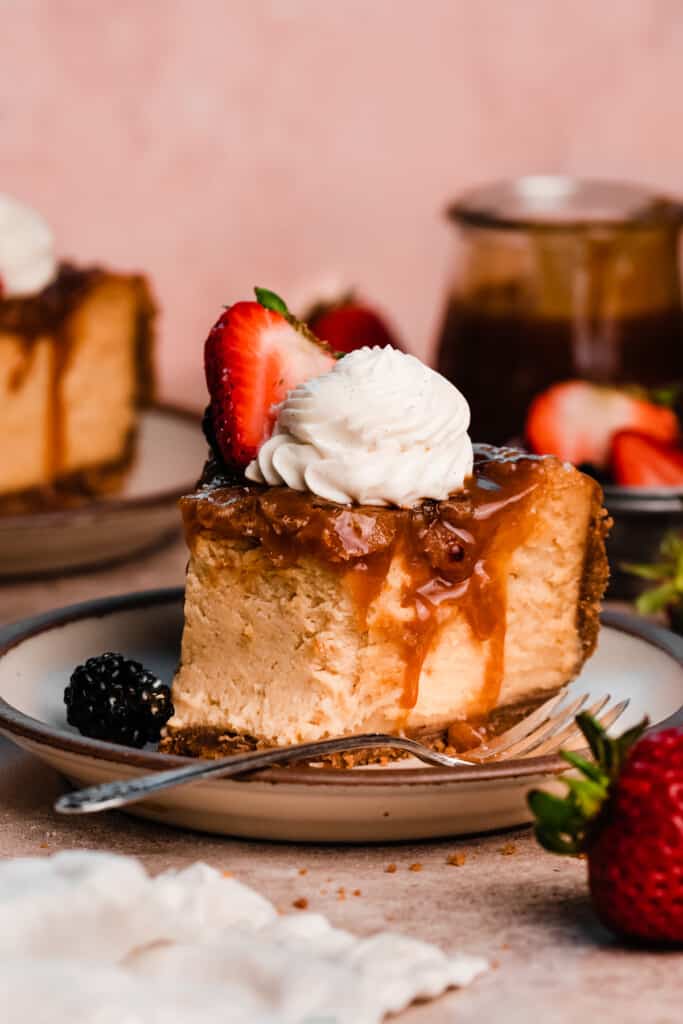 A slice of caramel creme brûlée cheesecake on a plate, with a bite missing to reveal the creamy insides. 