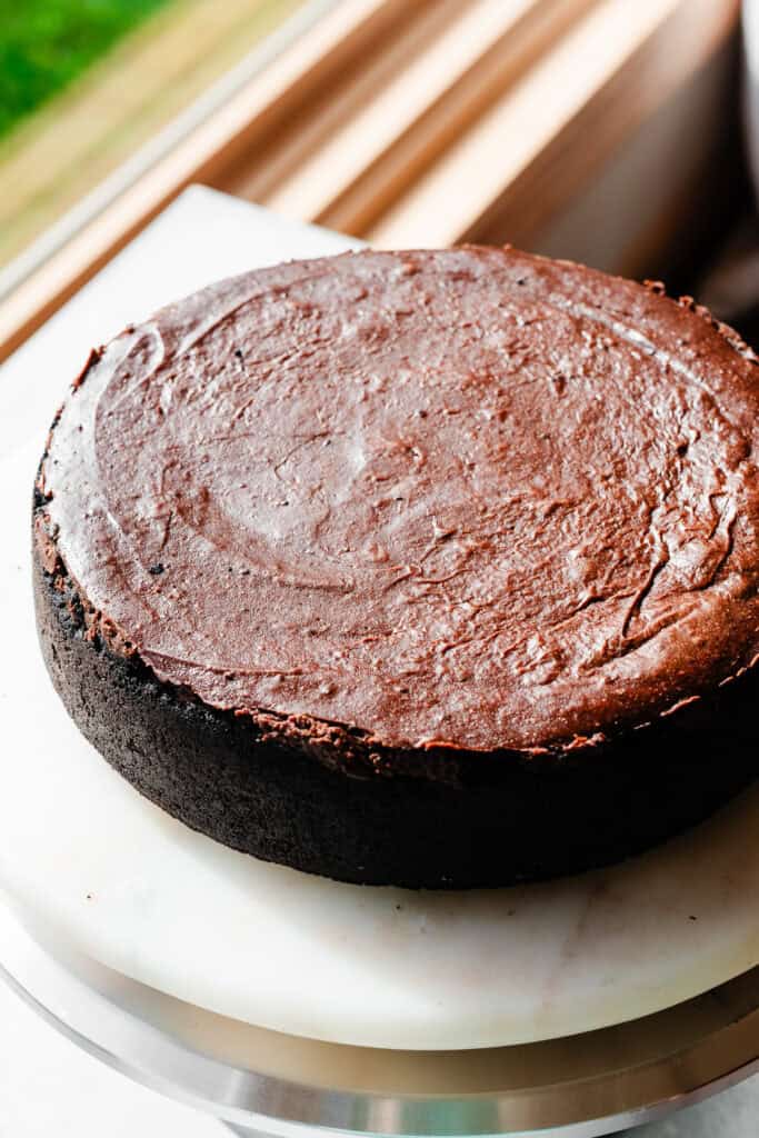 The baked and cooled cheesecake on a marble cake plate.