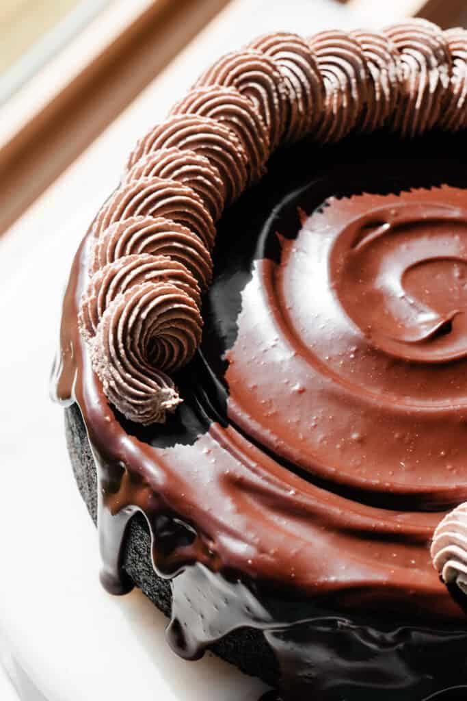Chocolate whipped cream being piped onto the chocolate cheesecake.