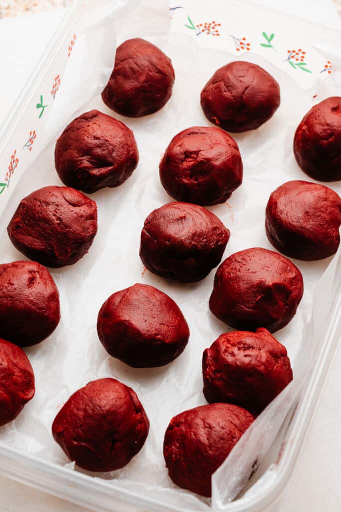 Red velvet cookie dough balls in a tupperware container.
