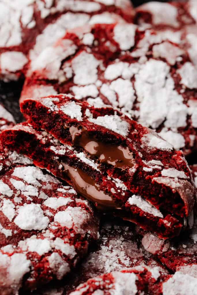 A red velvet lava cookie broken in half, with the molten nutella gently spilling out.