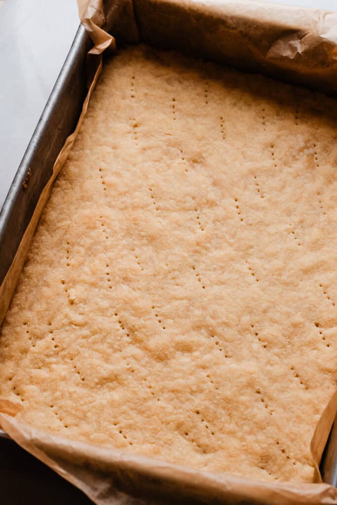 A pan of the baked shortbread crust, pricked all over with a fork.